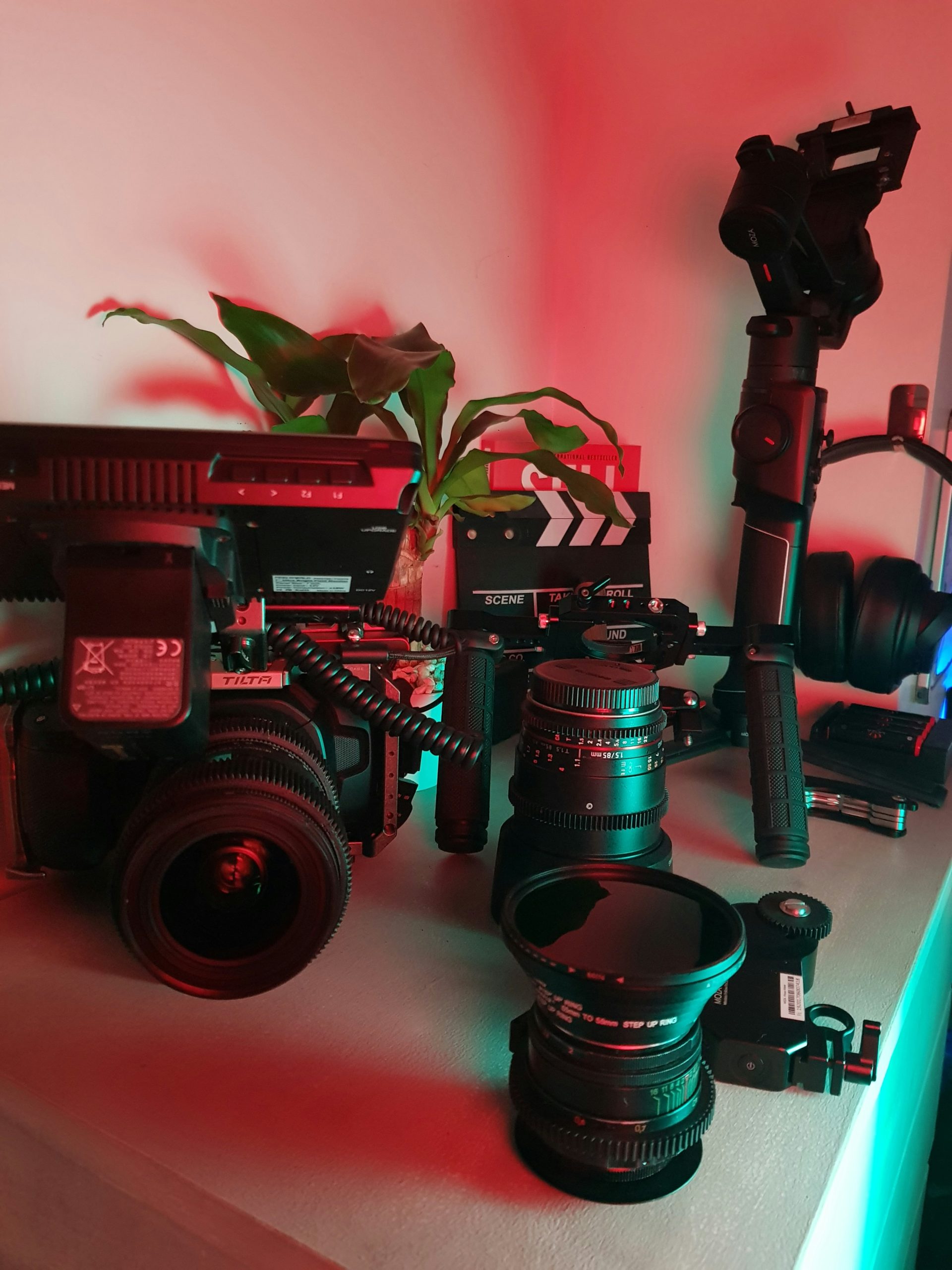 Professional photography equipment setup with cinematic lighting including cameras, lenses, and gimbal stabilizer in a creative studio environment