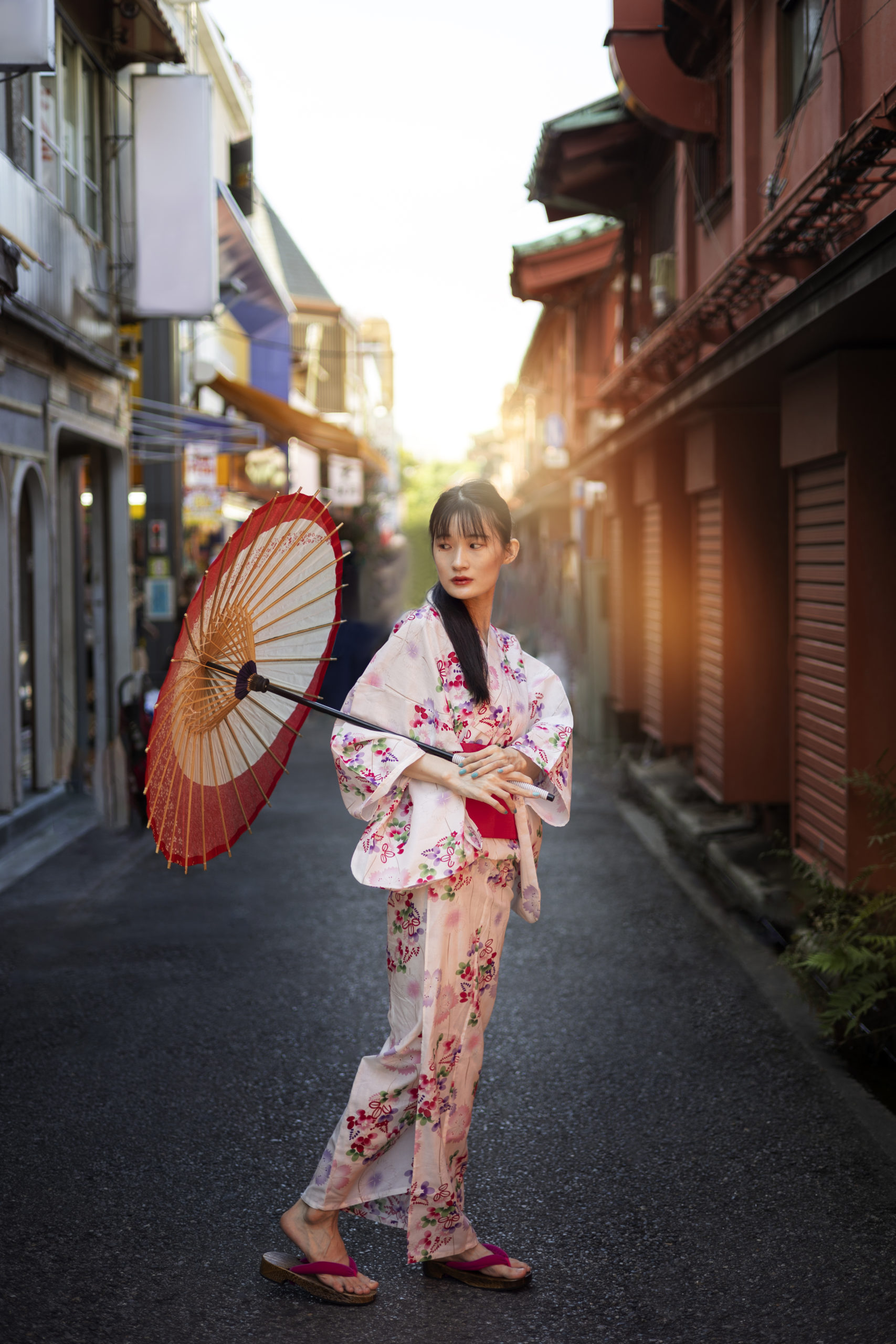 Beautiful woman in traditional pink kimono walking through historic Kyoto streets during cherry blossom season, showcasing the perfect kimono rental experience