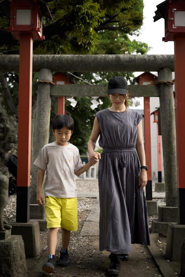 Elegant woman in traditional red and gold kimono walking through the famous vermilion torii gates at Fushimi Inari Shrine in Kyoto, showcasing the perfect blend of traditional Japanese dress and sacred Shinto architecture