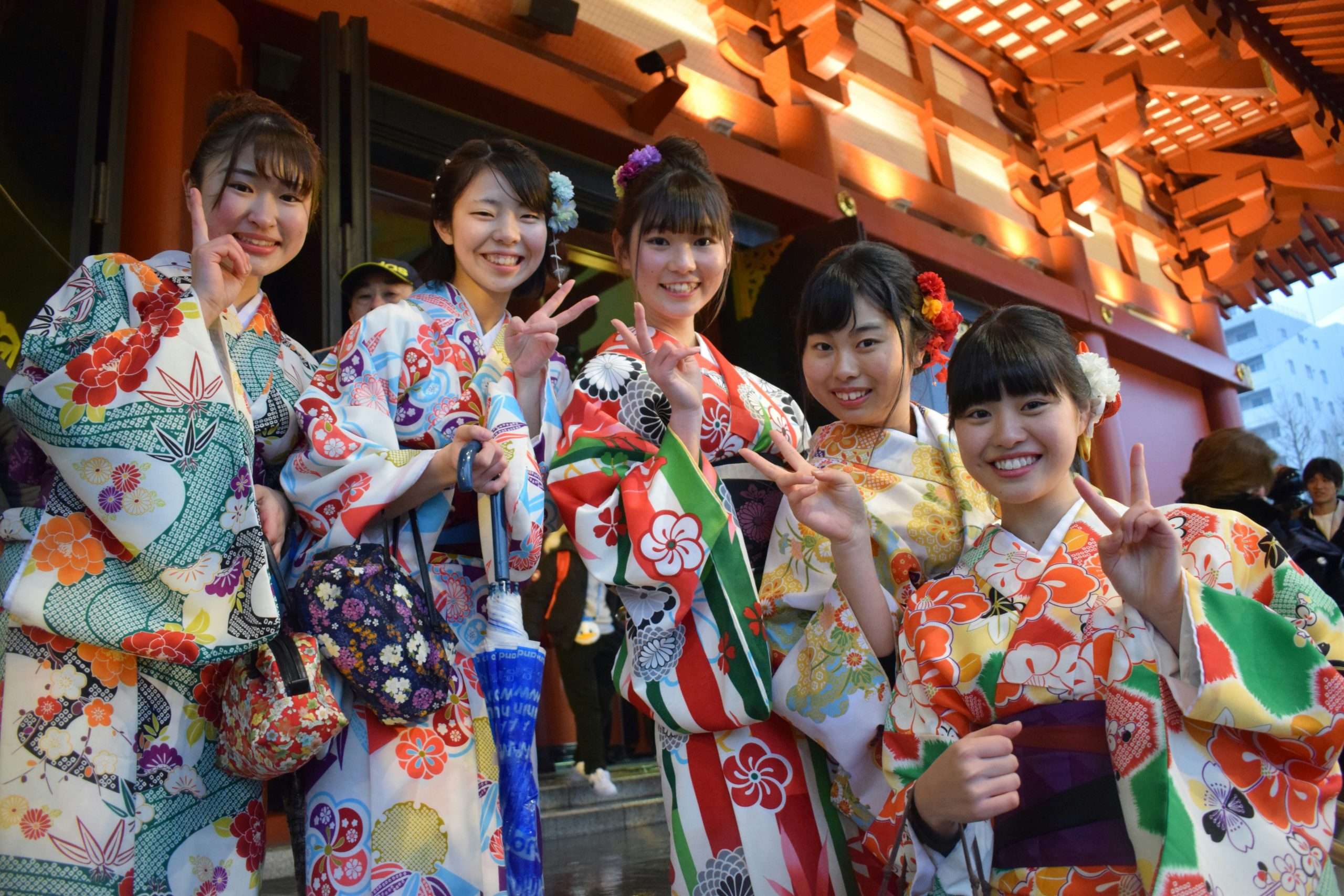 Traditional Japanese women in elegant kimono walking through historic Gion district at night with lantern-lit streets in Kyoto