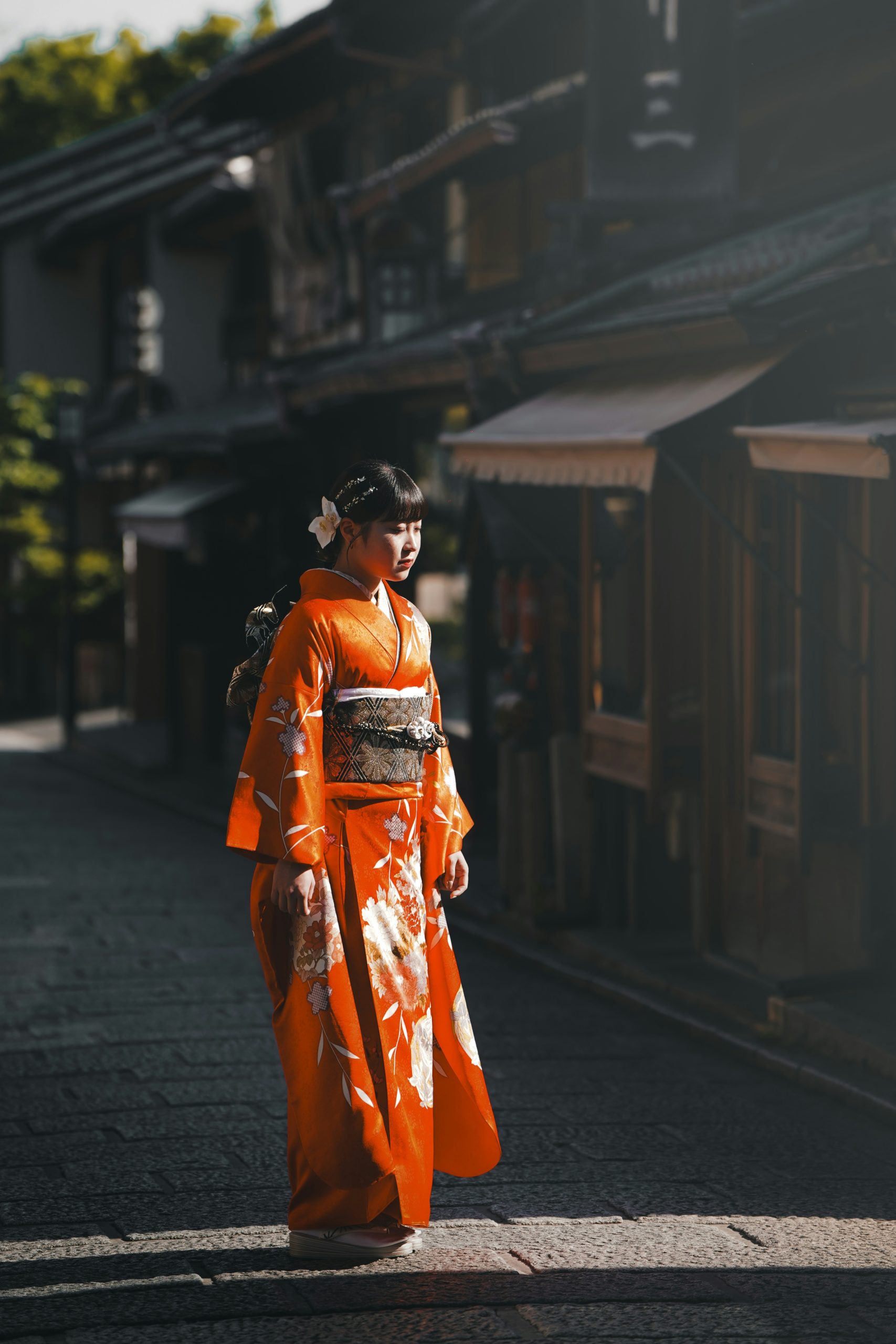 Two elegant young women wearing traditional colorful kimonos walking through the historic Gion district in Kyoto, Japan, showcasing the timeless beauty of Japanese traditional dress against historic wooden architecture