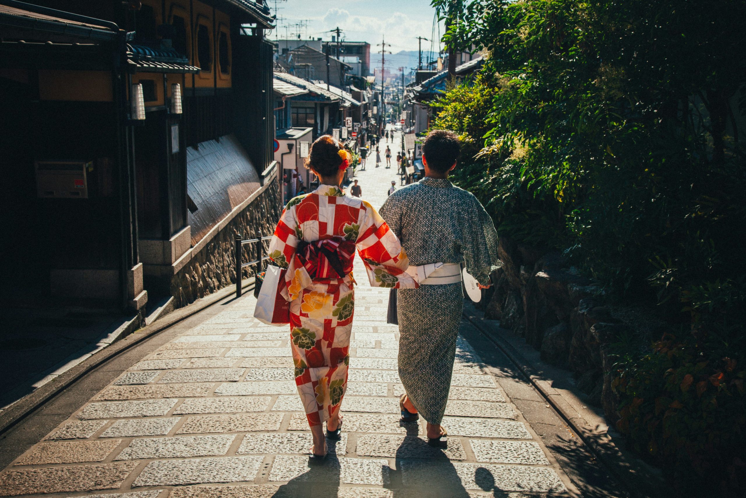 Romantic couple in matching traditional kimonos walking hand in hand near the famous Yasaka Shrine in Kyoto's Gion district, representing modern romance intertwined with Japanese cultural traditions